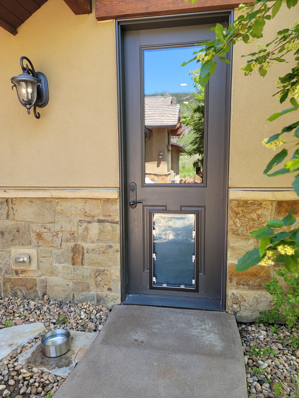 Dog door installed in a door in a house exterior with stone wall and garden view